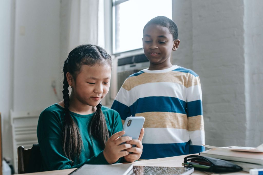 two kids looking at a phone